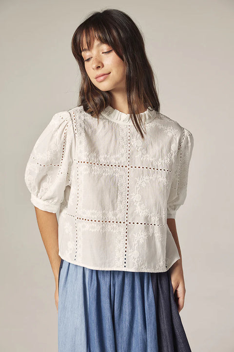 White embroidered eyelet blouse with puff sleeves angled front view. 100% Cotton.