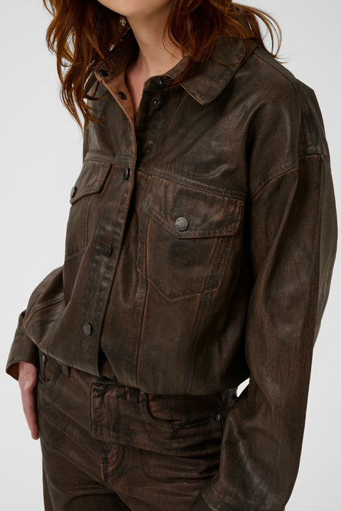 Chocolate brown coated denim jacket with a vintage waist-length cut, puckered hem, and snap buttons.