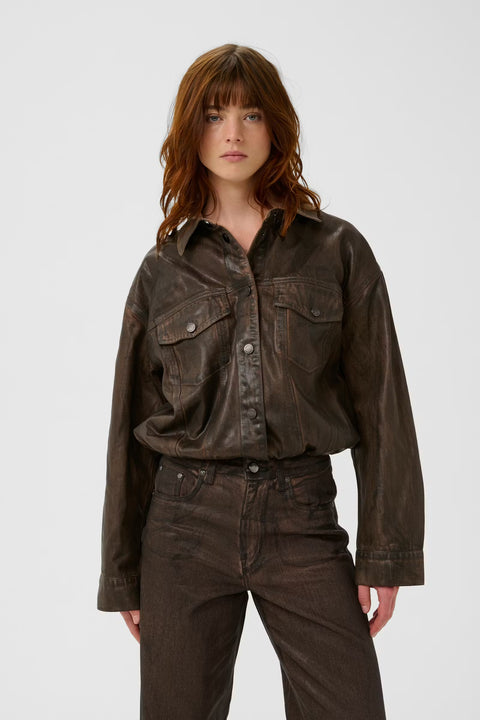 Chocolate brown coated denim jacket with a vintage waist-length cut, puckered hem, and snap buttons.
