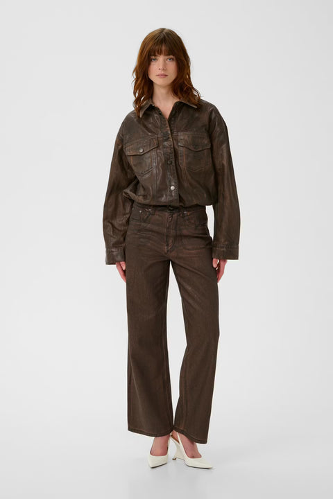 Chocolate brown coated denim jacket with a vintage waist-length cut, puckered hem, and snap buttons.