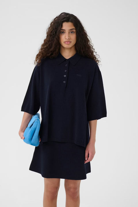 Black wool knit polo shirt with a boxy silhouette, dropped shoulders, five-button placket, and elbow-length wide sleeves.