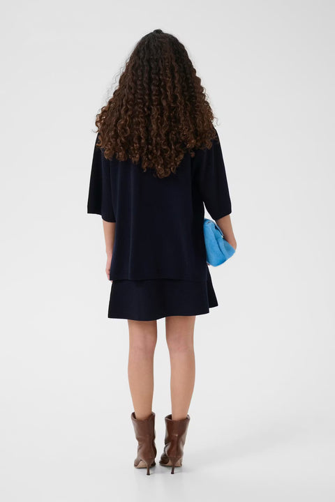 Black wool knit polo shirt with a boxy silhouette, dropped shoulders, five-button placket, and elbow-length wide sleeves.
