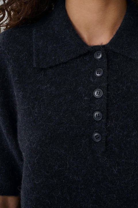 Black wool knit polo shirt with a boxy silhouette, dropped shoulders, five-button placket, and elbow-length wide sleeves.
