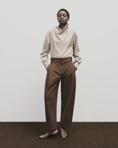 High-waisted, barrel-legged pants. Pleat detail at the hip and side seam pockets, pants cut at ankle.Mijeong Park Pleated Barrel-Leg Pants in Brown