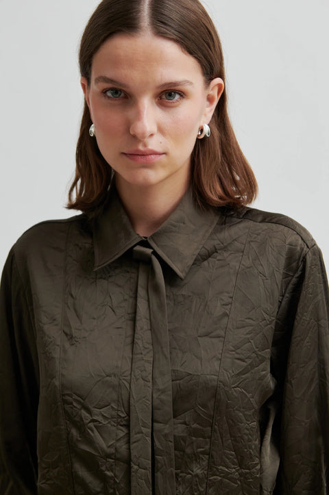 classic blouse cut from crinkle fabric, in dark olive colour. regular collar and concealed button placket, detachable neck tie and side-waist buttons to nip the waist for an adjustable silhouette