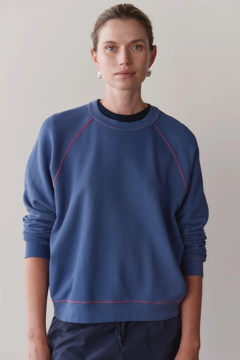Front view of DONNI lapis blue eco terry sweatshirt with raspberry contrast stitch detail – relaxed fit organic cotton top