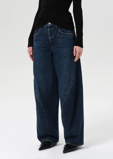 Model wearing AGOLDE Twist relaxed fit dark indigo jeans with twisted outseam
