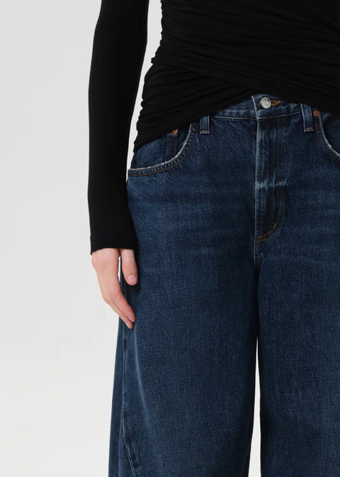 Model wearing AGOLDE Twist relaxed fit dark indigo jeans with twisted outseam