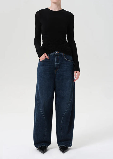 Model wearing AGOLDE Twist relaxed fit dark indigo jeans with twisted outseam