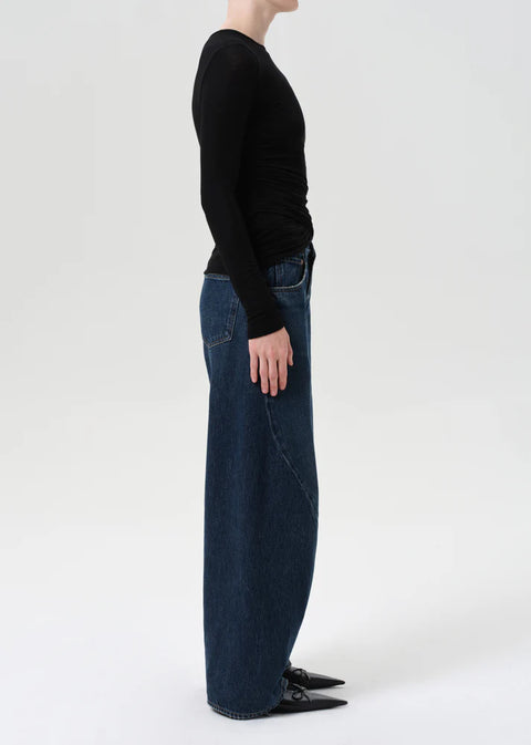 Model wearing AGOLDE Twist relaxed fit dark indigo jeans with twisted outseam