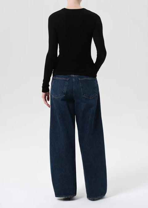 Model wearing AGOLDE Twist relaxed fit dark indigo jeans with twisted outseam