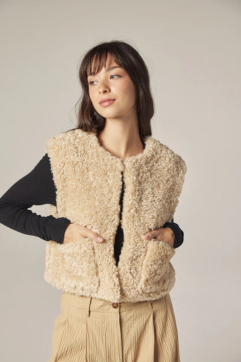 Woman wearing Amente reversible vest, one side faux fur oatmeal, other side cotton beige