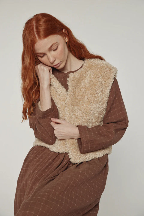 Woman wearing Amente reversible vest, one side faux fur oatmeal, other side cotton beige