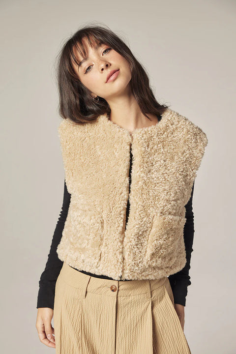 Woman wearing Amente reversible vest, one side faux fur oatmeal, other side cotton beige