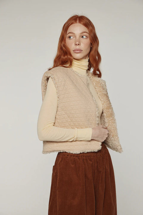 Woman wearing Amente reversible vest, one side faux fur oatmeal, other side cotton beige