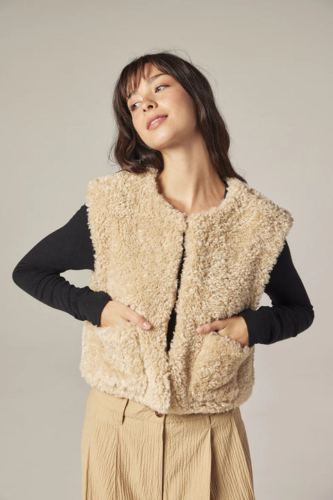 Woman wearing Amente reversible vest, one side faux fur oatmeal, other side cotton beige