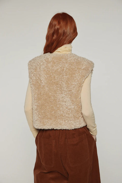 Woman wearing Amente reversible vest, one side faux fur oatmeal, other side cotton beige