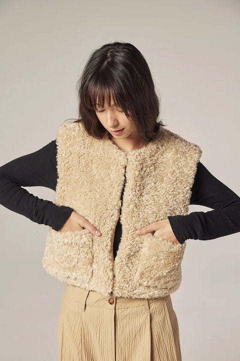 Woman wearing Amente reversible vest, one side faux fur oatmeal, other side cotton beige