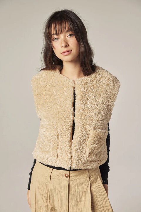 Woman wearing Amente reversible vest, one side faux fur oatmeal, other side cotton beige