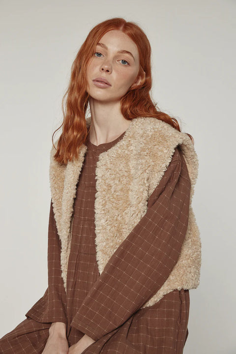 Woman wearing Amente reversible vest, one side faux fur oatmeal, other side cotton beige