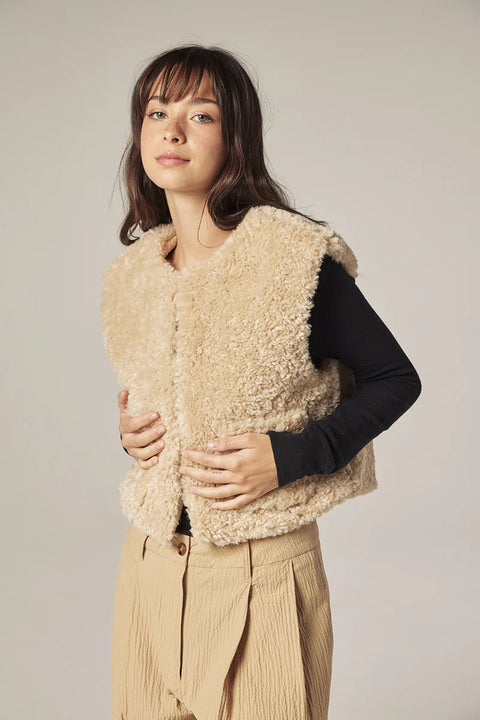 Woman wearing Amente reversible vest, one side faux fur oatmeal, other side cotton beige