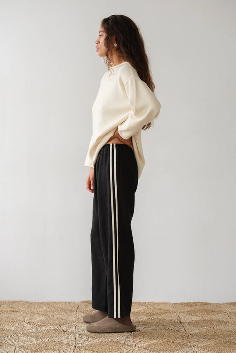 lightweight linen cropped pants in black with double white strip down the leg. Elastic waistband and cropped inseam and a wide leg fit. 
