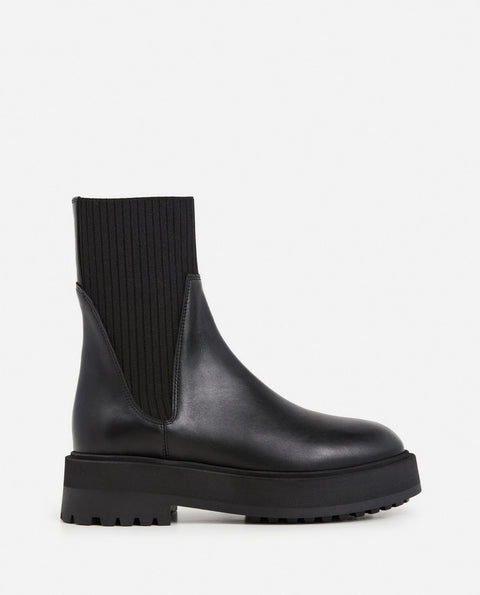 Platform black leather boots with knit paneling up the ankle, pull on style. Made by flattered. rubber sole and leather upper