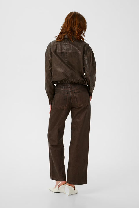 Chocolate brown coated denim jacket with a vintage waist-length cut, puckered hem, and snap buttons.
