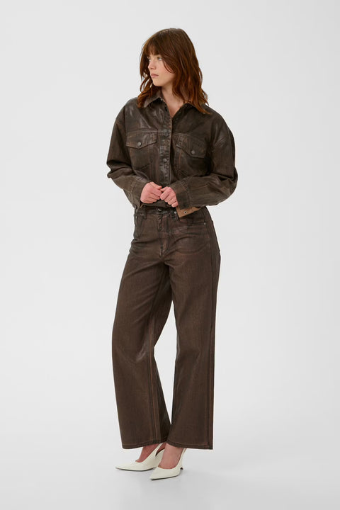 Chocolate brown coated denim jacket with a vintage waist-length cut, puckered hem, and snap buttons.
