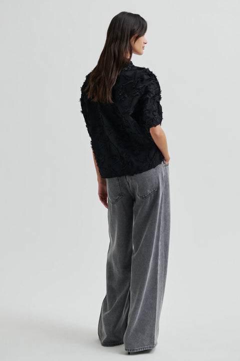 Textured leaf pattern short sleeve cotton sweater in black, button-through placket, and short sleeves with an elastic, ruched detail.
