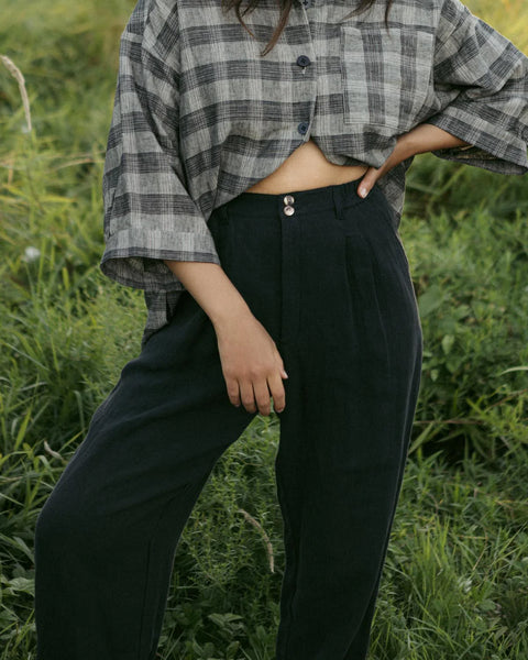 A pair of Thorne Trousers in 100% linen twill featuring a comfortable three-quarter elastic waistband, front pleats, and a vintage-inspired shell button closure.