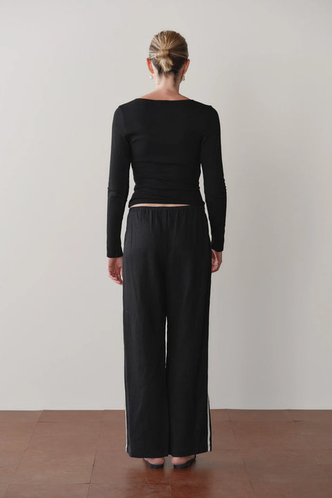 Close-up of DONNI racer stripe linen pant in Jet Black showing elasticated waistband and cropped hem detail